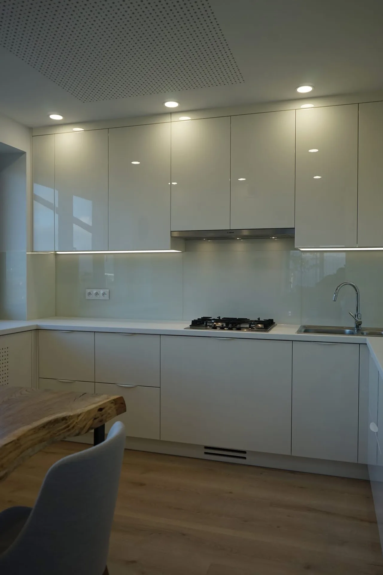 Moderne witte keuken met glazen achterwand