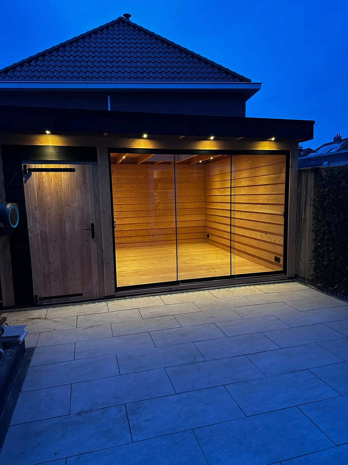 Verlichte moderne tuinkamer met glazen deuren