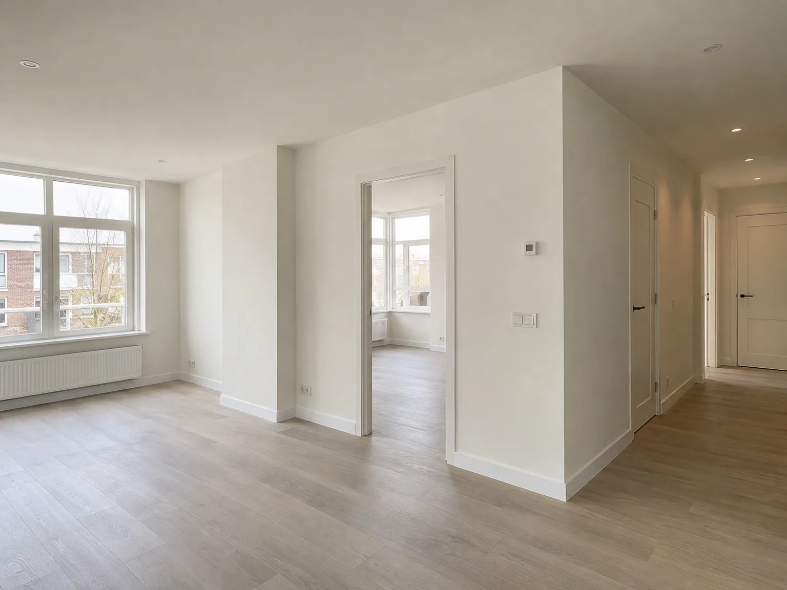 Oplevering nieuwbouw: afgewerkte woonkamer met laminaatvloer en witte gipsplaten wanden