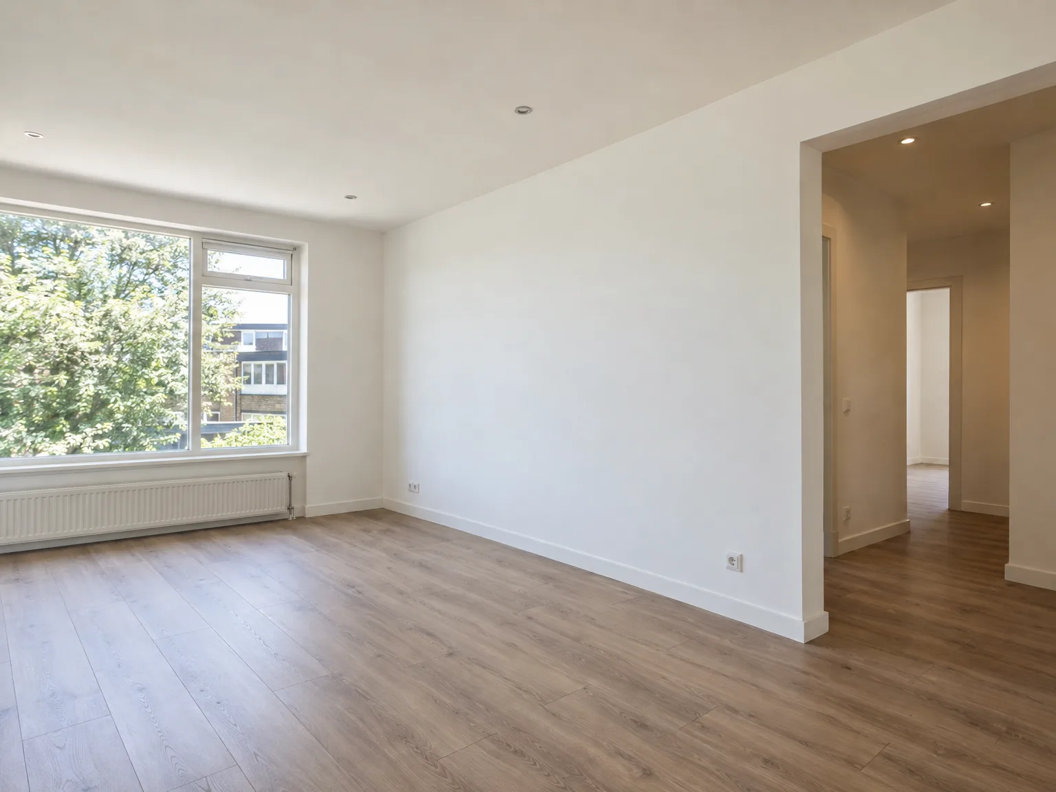 Nieuw afgebouwd woonkamer met gipsplaten wanden, verlaagd plafond, laminaatvloer en grote ramen met natuurlijk licht