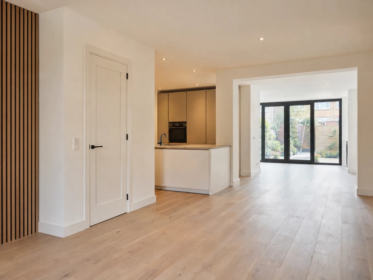 Moderne woonkamer met houten vloer, eilandkeuken en grote glazen deuren