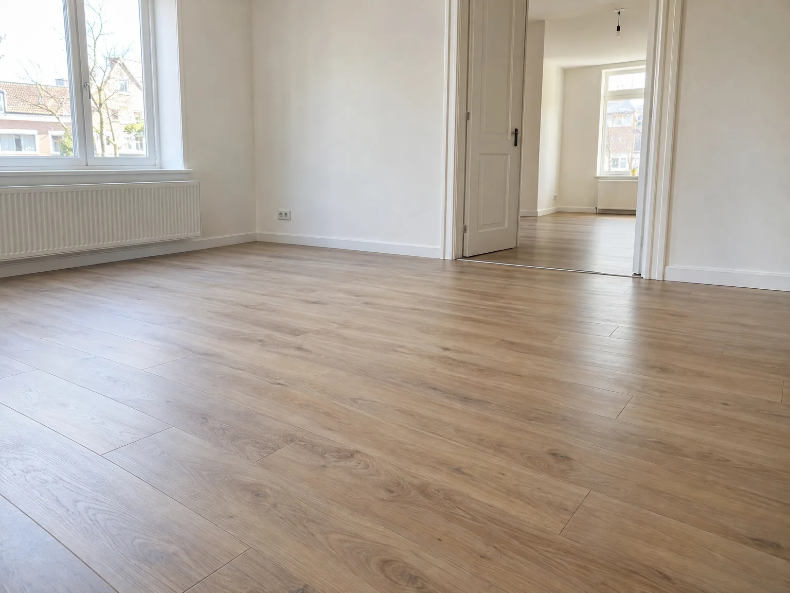 Gerenoveerde woonkamer met nieuwe laminaatvloer en strakke witwerk afwerking