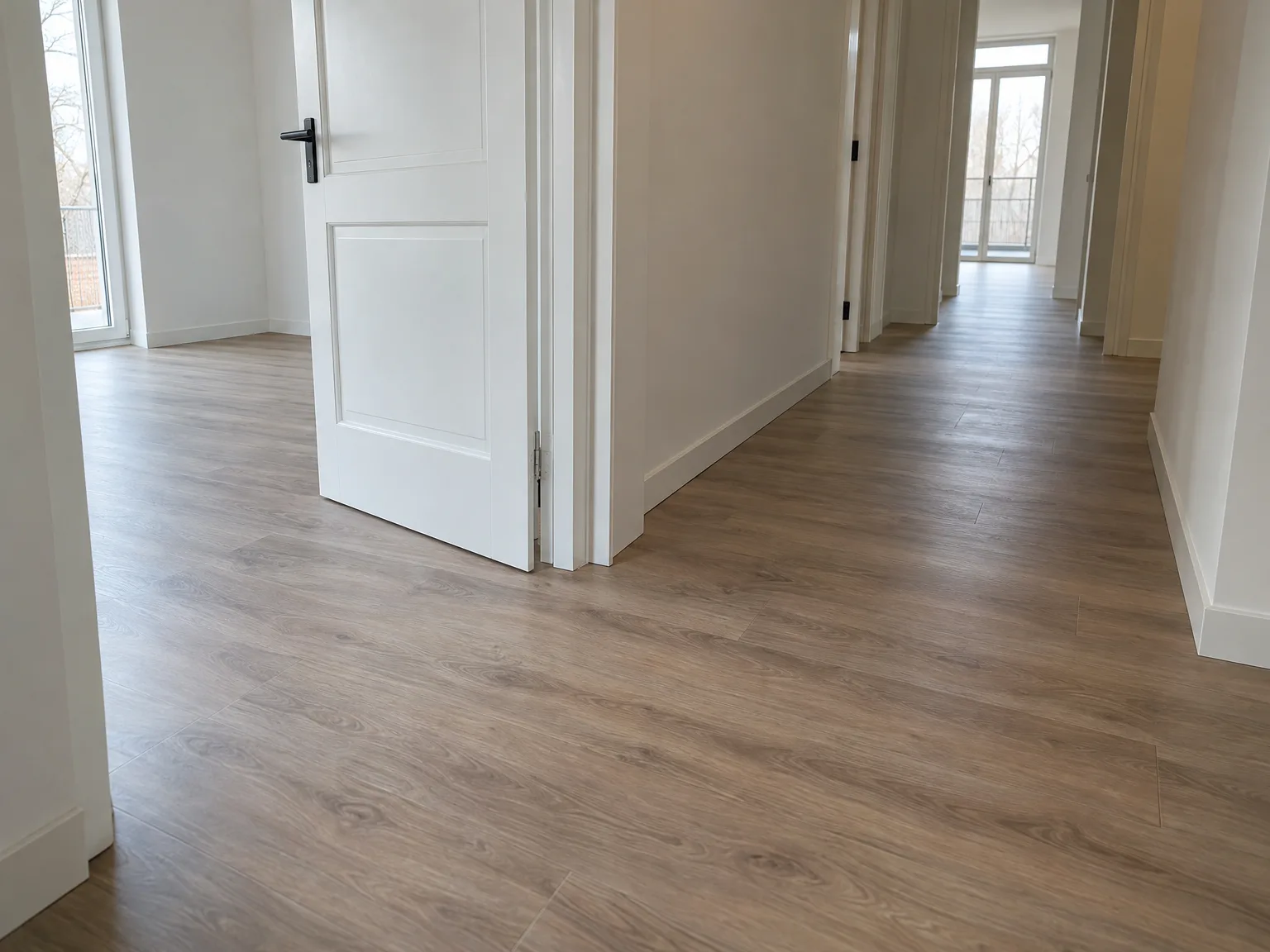 Gelegde laminaatvloer in afgewerkt interieur met witte deuren en muren
