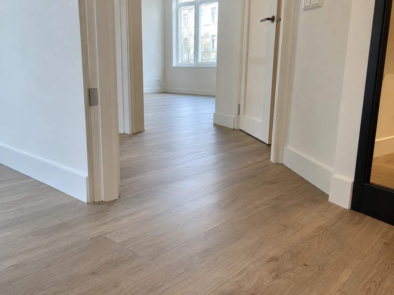 Laminaatvloer in nieuw wooninterieur met witte muren, deuren en ramen