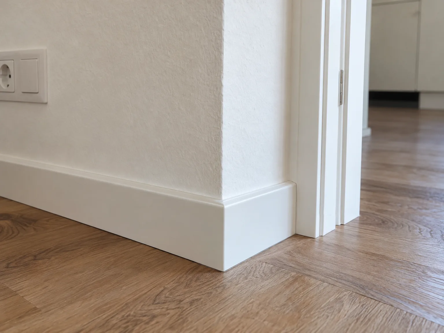 Detailafwerking: laminaatvloer met witte plint en deurkozijn
