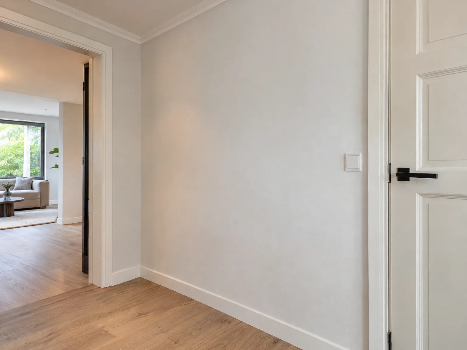 Afgewerkt interieur met gipsplaten wanden, houten vloer en witte deurkolijsten na renovatie