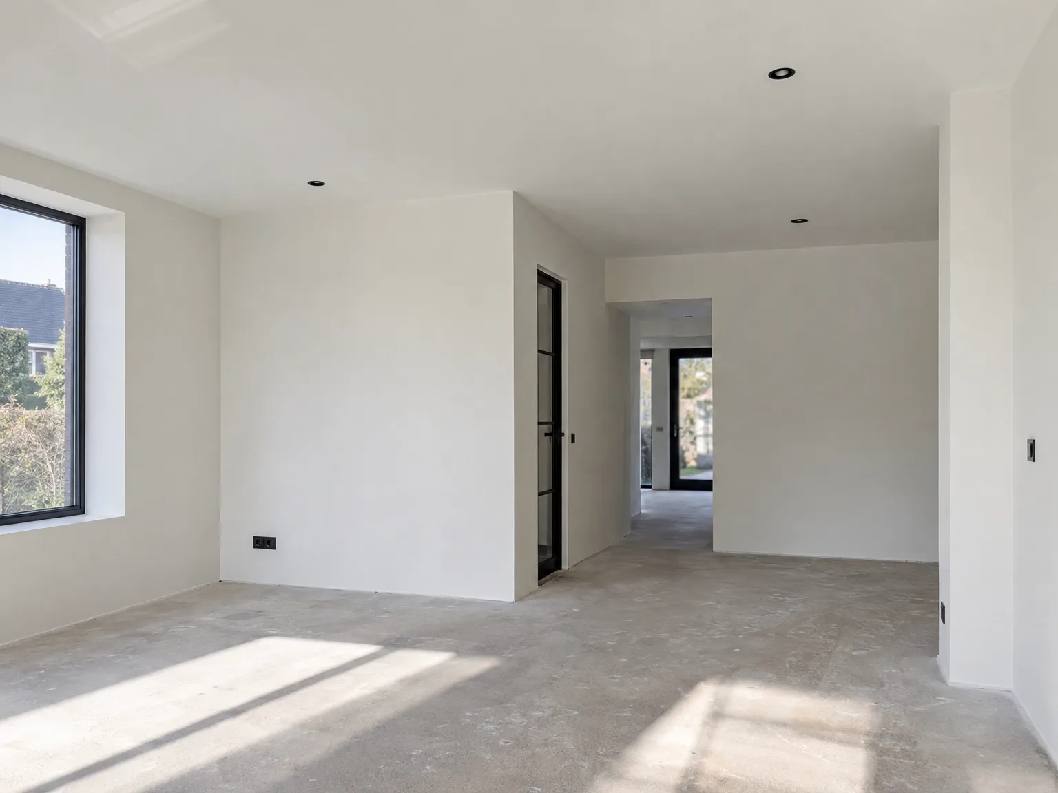 Nieuwbouw interieur met gipsplaten afwerking en betonnen vloer gereed voor verdere verwerking