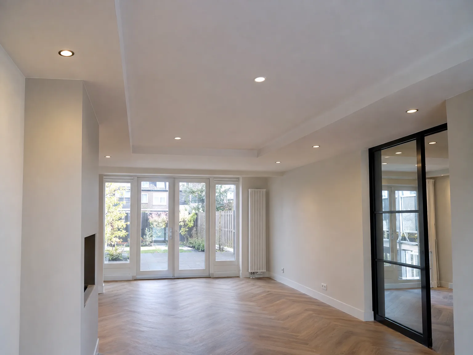 Afgewerkt interieur met parketvloer, grote glazen schuifdeuren en modern verlicht plafond