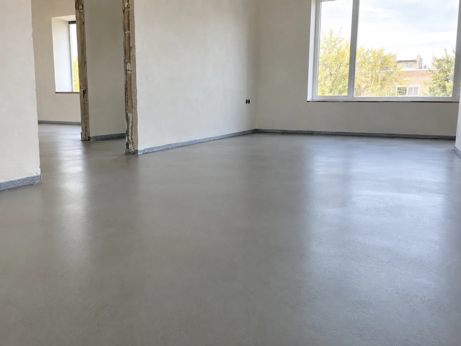 Oplevering nieuwbouw: lege ruimte met uitgeëffende vloer, witte wanden en grote ramen