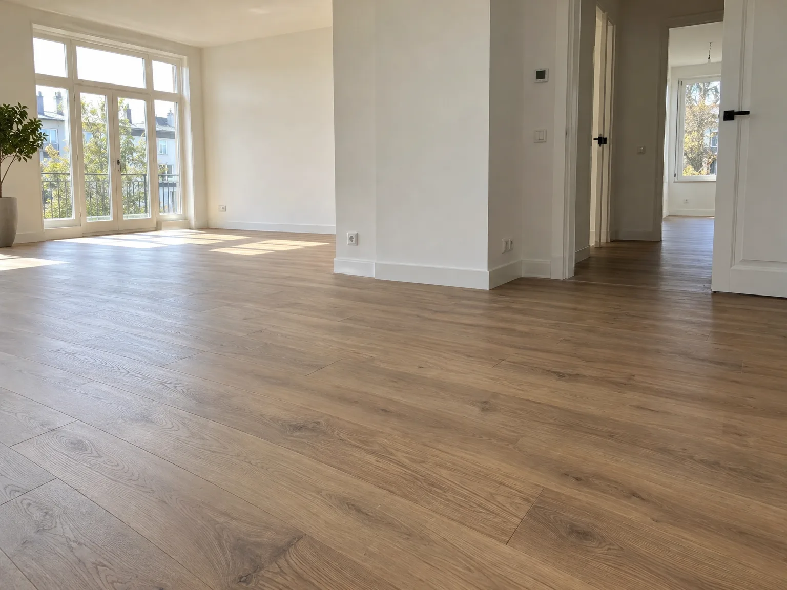Woonkamer na verbouwing met houten parketvloer, witte wanden en grote ramen