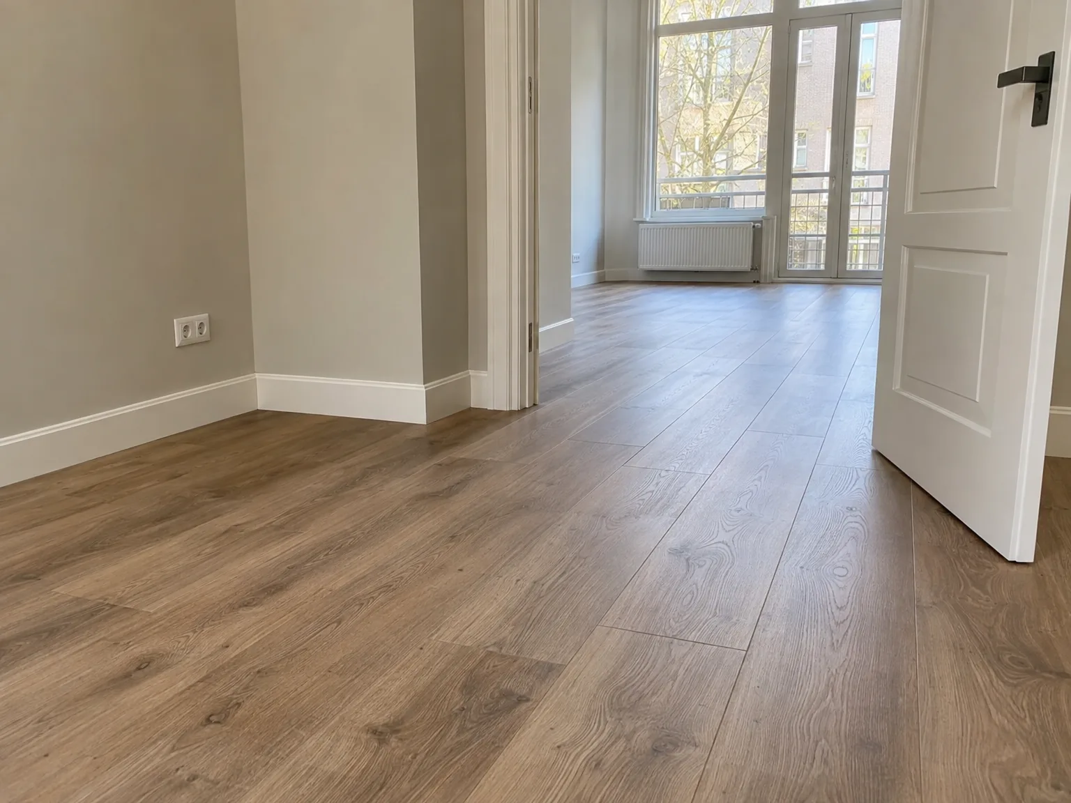 Nieuwe laminaatvloer in hal met witte afbouw en kozijnen